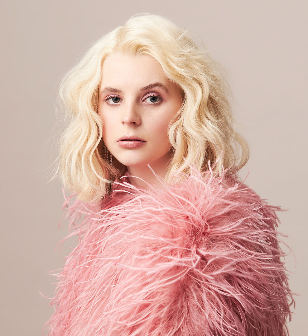 Portrait of a blonde woman adorned in a fluffy pink feathered garment